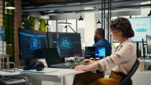 Woman analyzing AI data on multiple computer screens in modern office